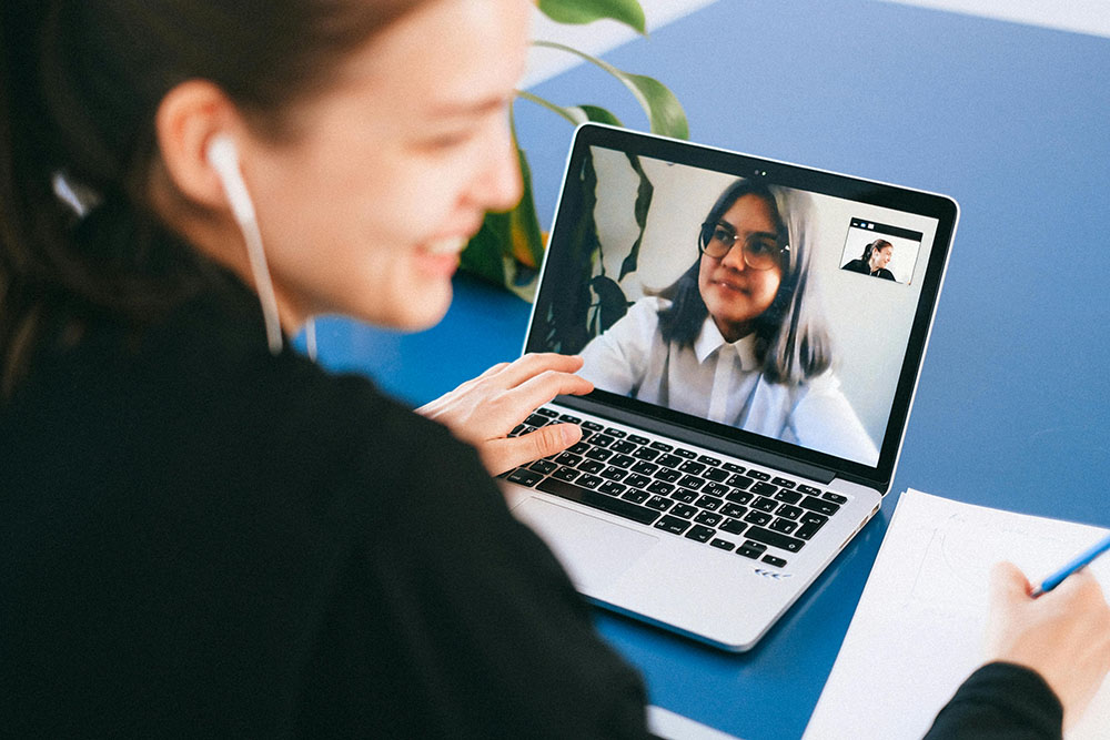 Remote team members engaged in a virtual meeting on their laptops.
